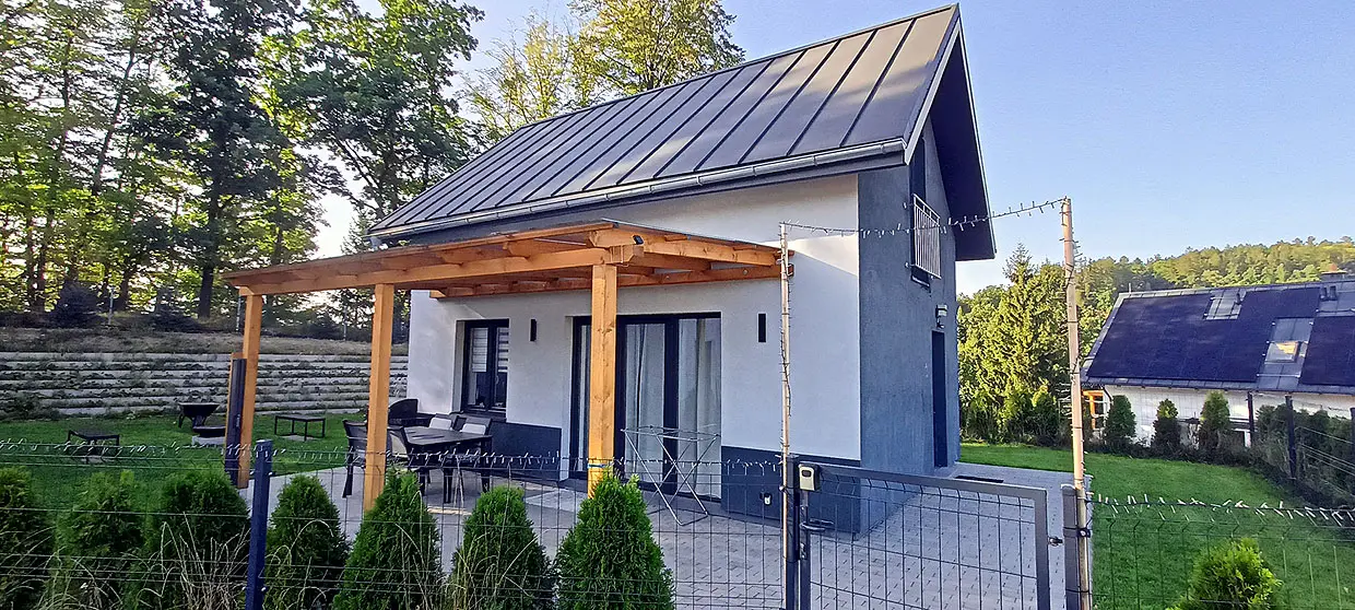 Domek Pine Peak w Sosnówce z drewnianą pergolą, a w tle dach z naszą instalacją fotowoltaiczną 14,5 kWp